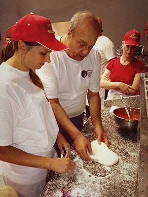 Two women learning how to make pizza